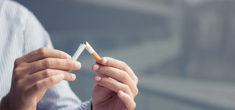 Une personne casse une cigarette pour arrêter de fumer.