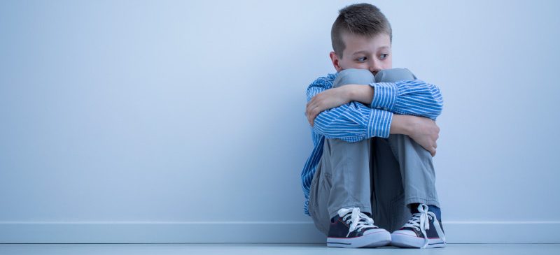 autistes : enfant assis la tête entre les genoux