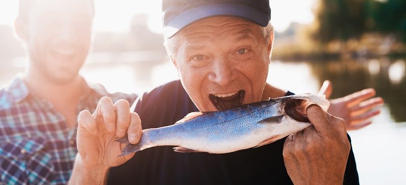 Un homme tient un poisson et prétend qu'il veut la manger