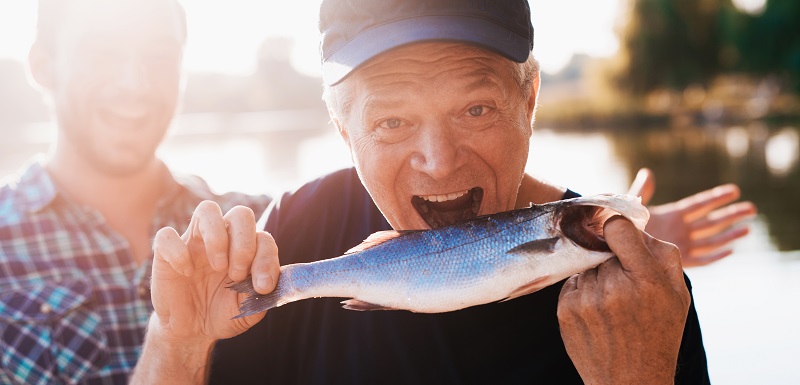 Un homme tient un poisson et prétend qu'il veut la manger