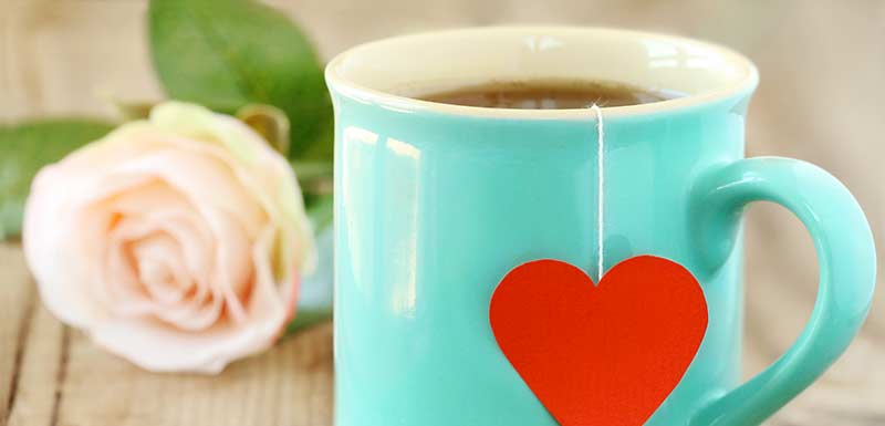 Une tasse avec un motif coeur contenant du thé vert