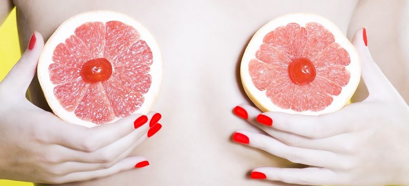 Une femme cache ses seins avec des fruits