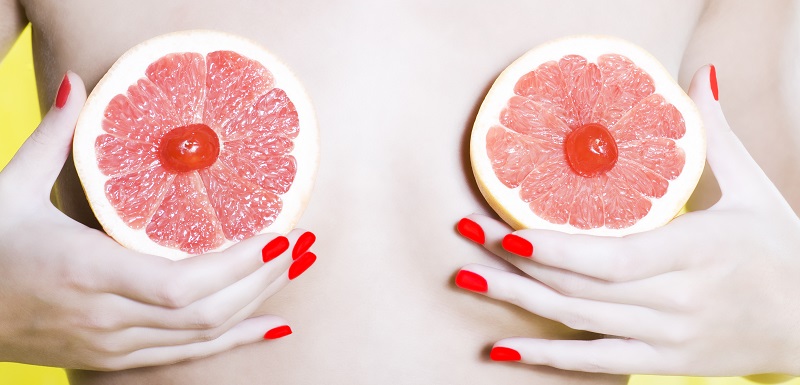 Une femme cache ses seins avec des fruits