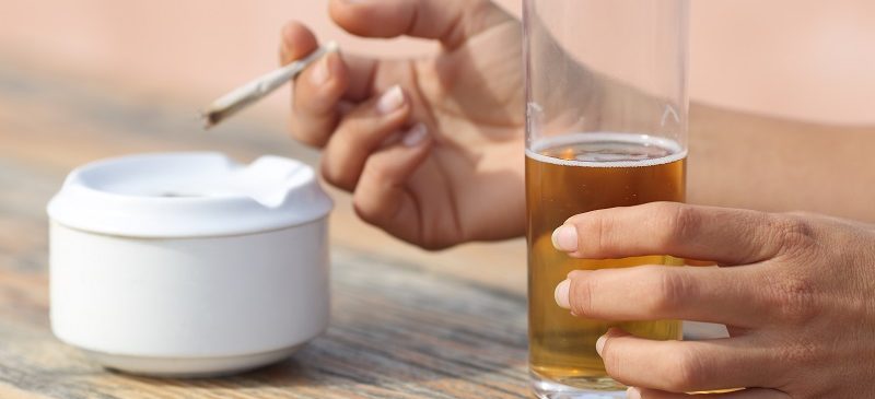 une femme avec une cigarette de tabac et un verre d'alcool