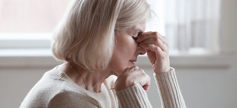 vielle femme fatiguée massant son nez