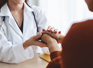 femme médecin massant la main d'une jeune femme à cause des rhumatismes