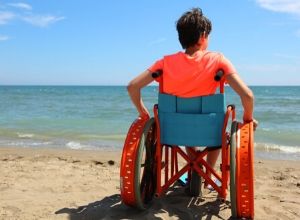 Petit garçon en fauteuil roulant à la plage suite à une dystrophie musculaire