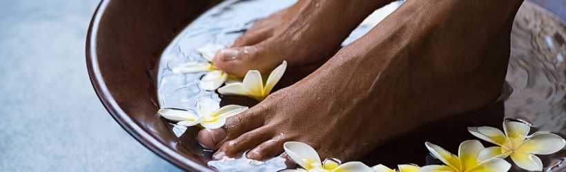 Bain de pieds dans de l'eau avec des fleurs pour se relaxer