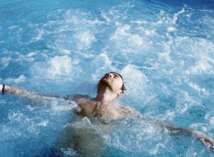 Jeune homme qui se détend au milieu d'un bain à remous