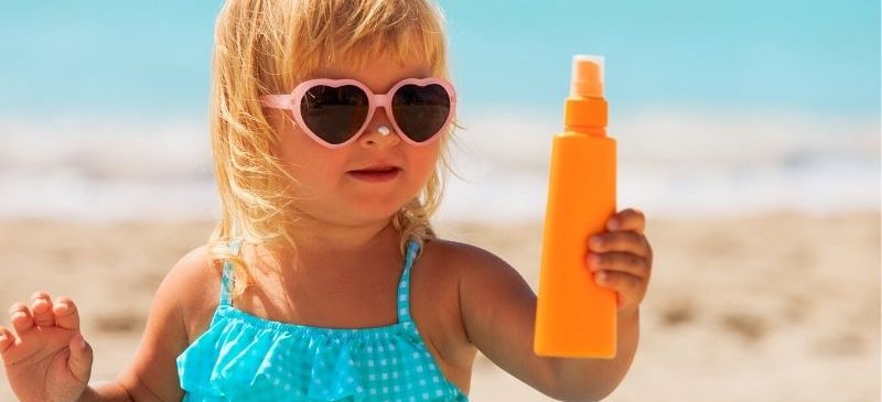 Petite fille qui joue avec un tube de crème solaire