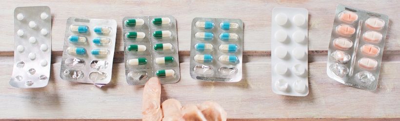 6 plaquettes de médicaments les unes à côté des autres, une personne âgée choisie sa plaquette