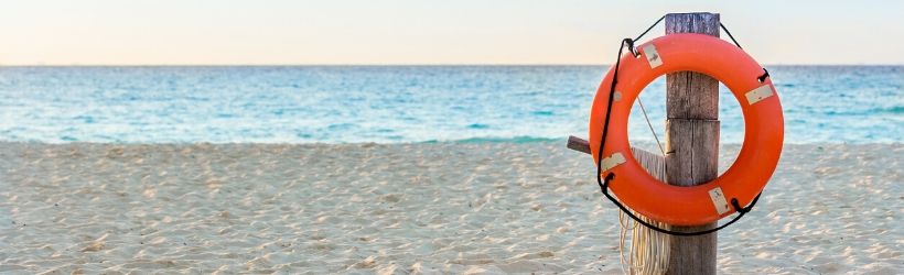 Bouée de sauvetage accrochée à un poteau de bois sur la plage