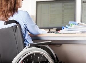 Femme qui travaille derrière un ordinateur en fauteuil roulant