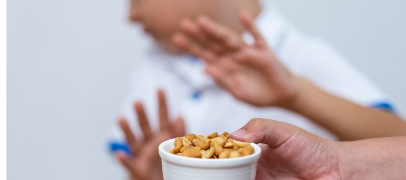 enfant repoussant un bol de cacahuètes