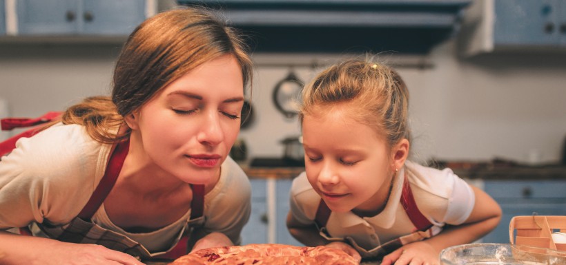 une femme et sa fille qui sentent un gâteau 