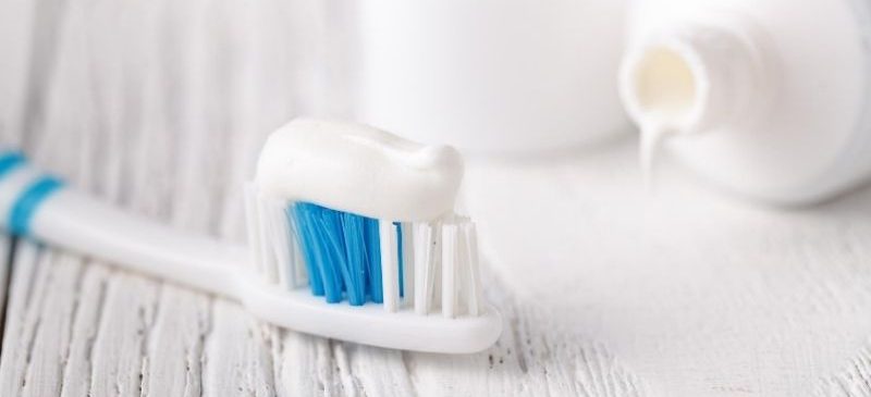 tubes dentifrices sans fluor, avec au premier plan une brosse à dent avec une noisette de pâte à dentifrice dessus