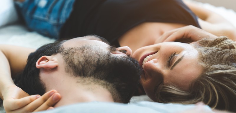 couple allongé sur un lit qui se regarde dans les yeux