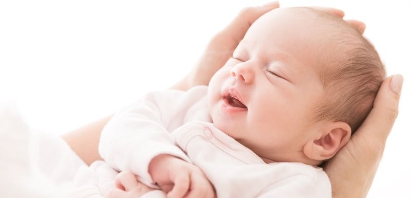 bébé qui dort dans les mains de sa maman