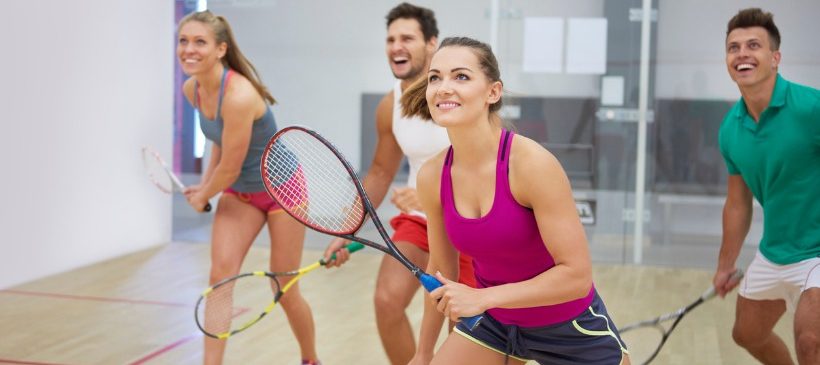 hommes et femmes qui jouent au squash en souriant