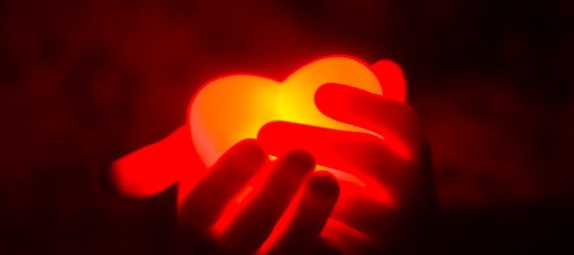 Coeur rouge fluorescent dans des mains