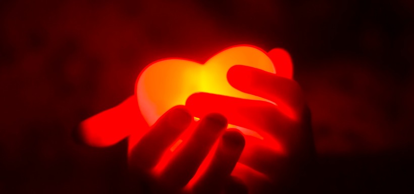 Coeur rouge fluorescent dans des mains 