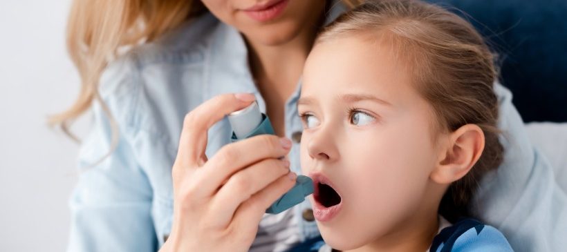 femme qui introduit un inhalateur dans la bouche de sa petite fille