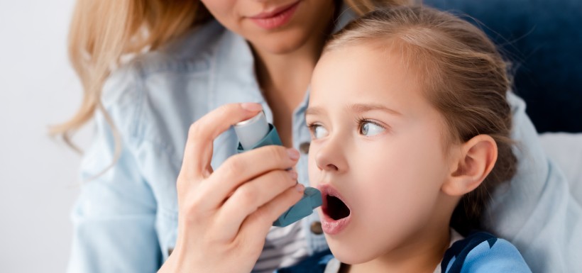 femme qui introduit un inhalateur dans la bouche de sa petite fille 