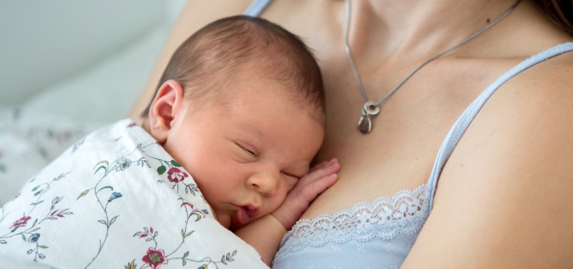 nourrisson en train de dormir dans les bras de sa maman 