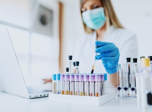 femme avec un masque prenant un tube à essai dans un laboratoire 