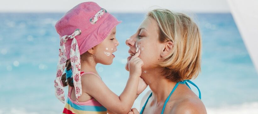 Petite fille appliquant de la crème solaire sur le visage de sa mère - octocrylène et crèmes solaires