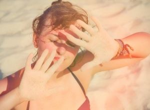 femme qui met ses mains devant les yeux pour se protéger du soleil