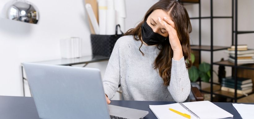 femme en train d'étudier avec son ordinateur et qui a mal à la tête