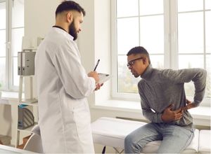 monsieur qui a mal au bas du dos assis chez le médecin