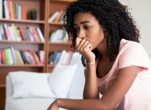 femme pensive assise sur son canapé