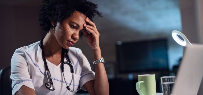 femme qui a mal à la tête en train de travailler sur son ordinateur