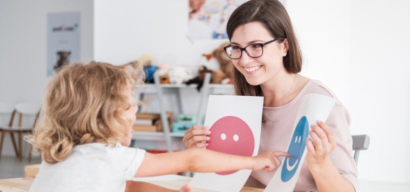 soignante en train de montrer des images à un enfant atteinte d’autisme TSA