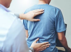 Monsieur chez le médecin qui montre son arthrose lombaire