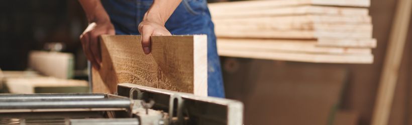 un maçon en train de couper une planche de bois