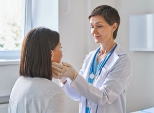 femme médecin qui touche les glandes thyroïdes d'un patient