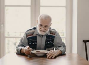 un homme âgé qui mange seul et souffre de dénutrition