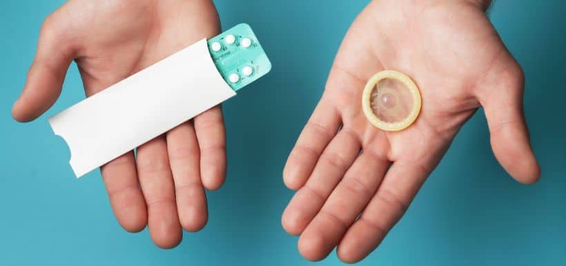 une personne tient dans ses mains la pilule et un préservatif par rapport à la journée mondiale de la contraception