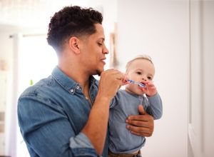 Homme qui brosse les dents de son bébé