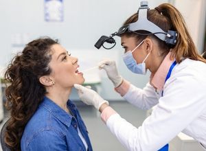 Un médecin ausculte la bouche d'une patient en raison d'une glossodynie.