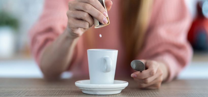 Femme mettant des édulcorants artificiels dans son café