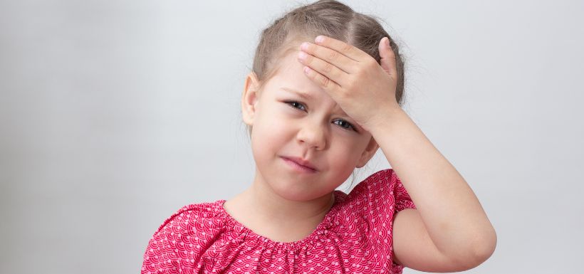 Petite fille se touchant la tête à cause d'une méningite bactérienne à méningocoque.